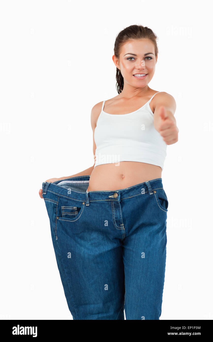 Portrait of a fit woman wearing too large jeans with the thumb up Stock Photo Alamy