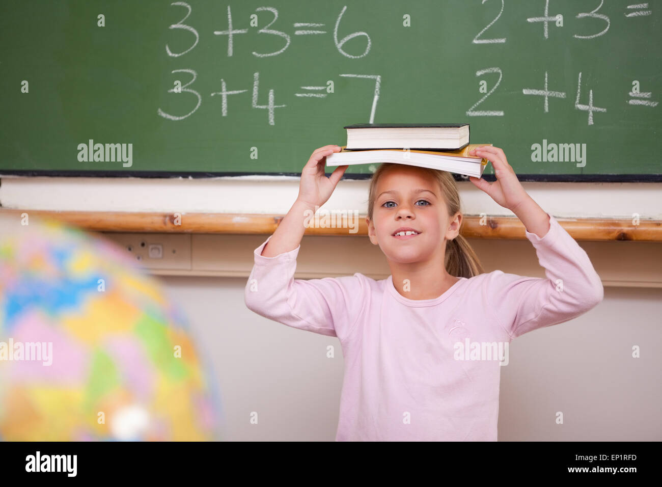 Smiling schoolgirl holding her book on her head Stock Photo - Alamy
