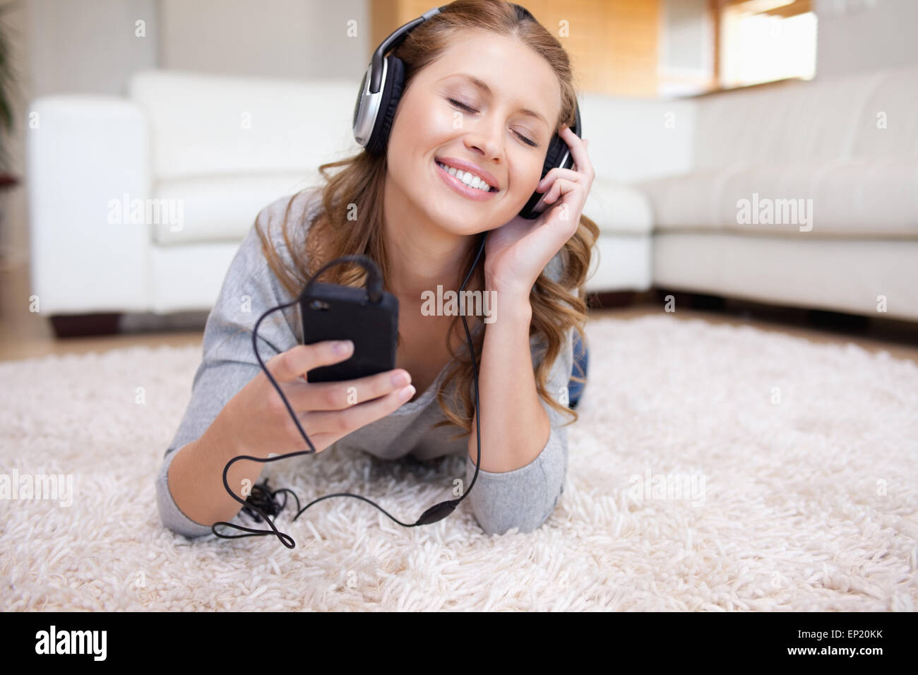 Young woman lying on the carpet listening to music Stock Photo - Alamy