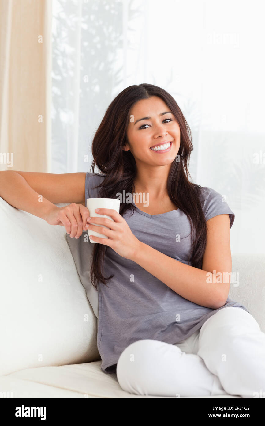 crossleged sitting woman with cup smiling into camera Stock Photo