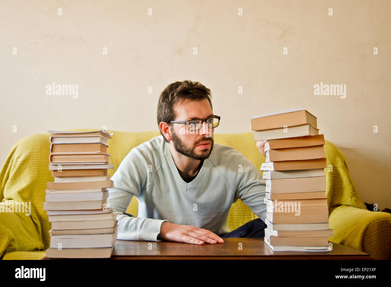 Man sitting with a pile of books Stock Photo