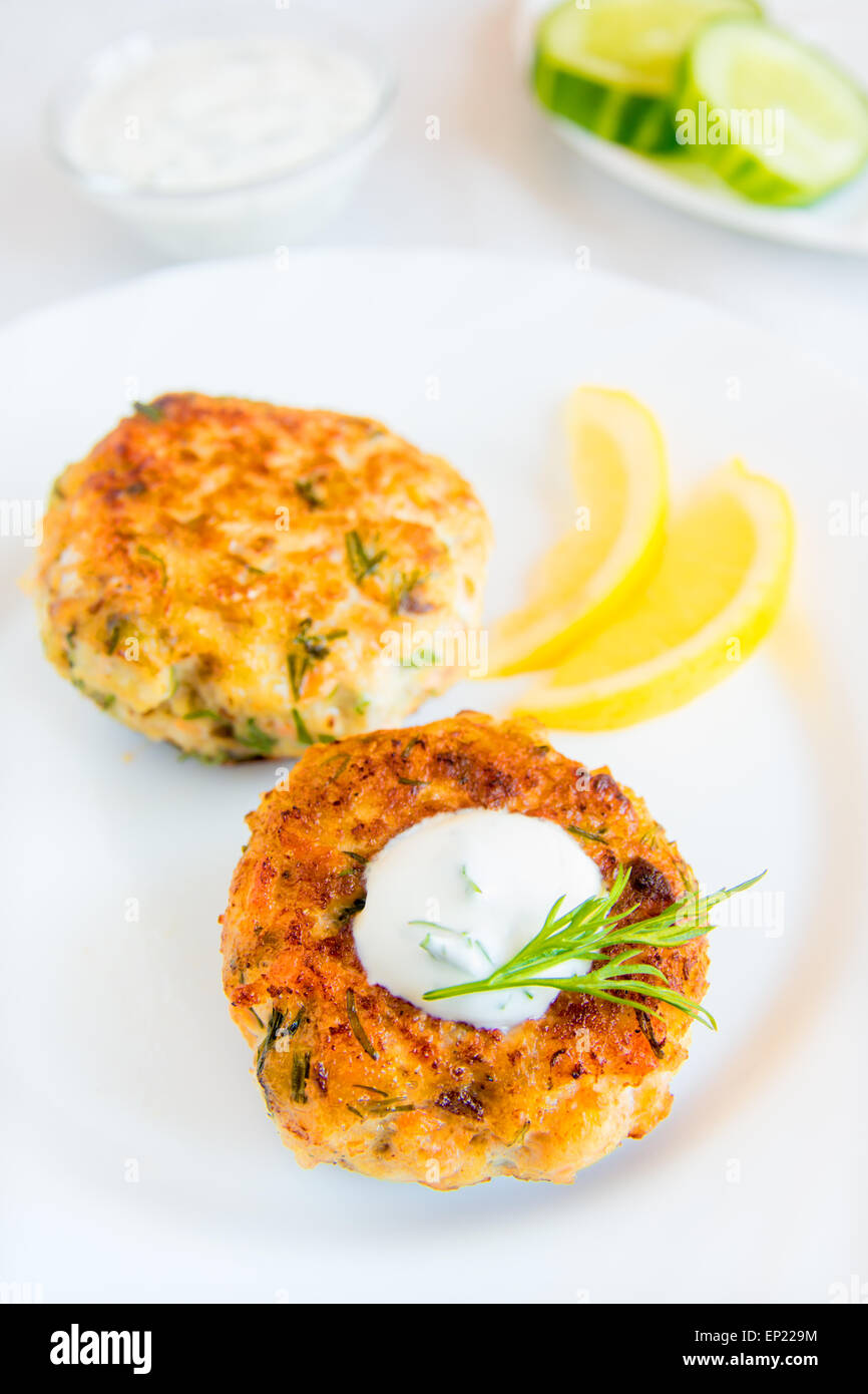 Homemade thai fish cakes (cutlets) with white sauce, dill and lemon on