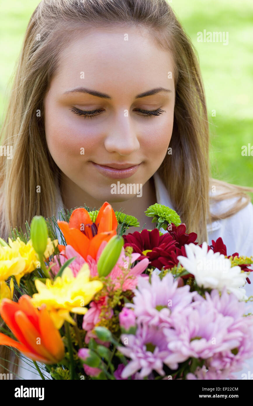 Young peaceful woman smelling a bunch of flowers while closing her eyes ...