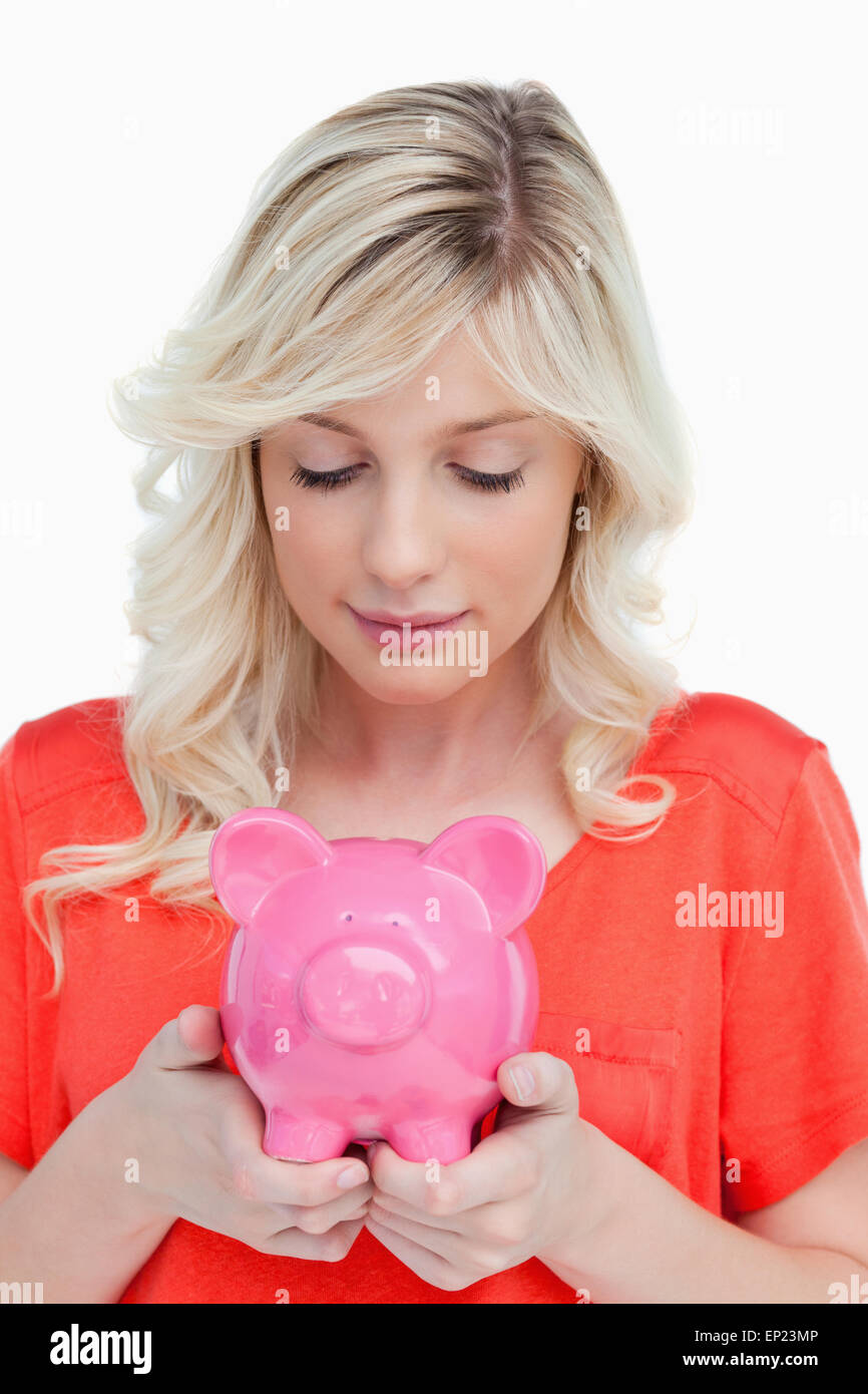 Young woman looking at a piggy bank held by her hands Stock Photo - Alamy