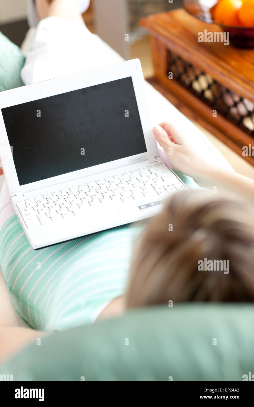 A woman using a laptop lying on a sofa Stock Photo - Alamy