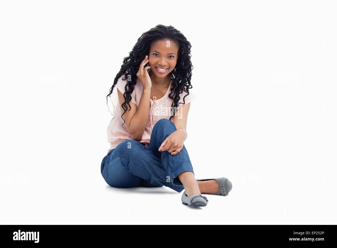 A woman smiling at the camera sitting on the floor is talking on her ...