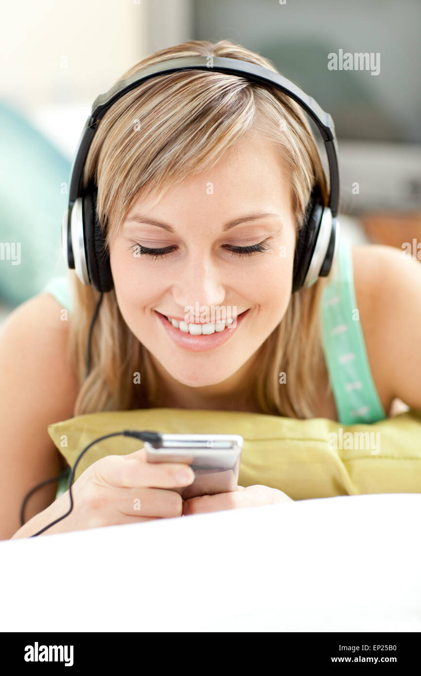 Smiling young woman listening music lying on a sofa Stock Photo - Alamy