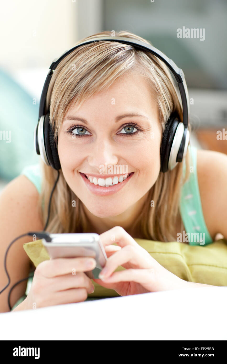 Charming young woman listening music lying on a sofa Stock Photo - Alamy