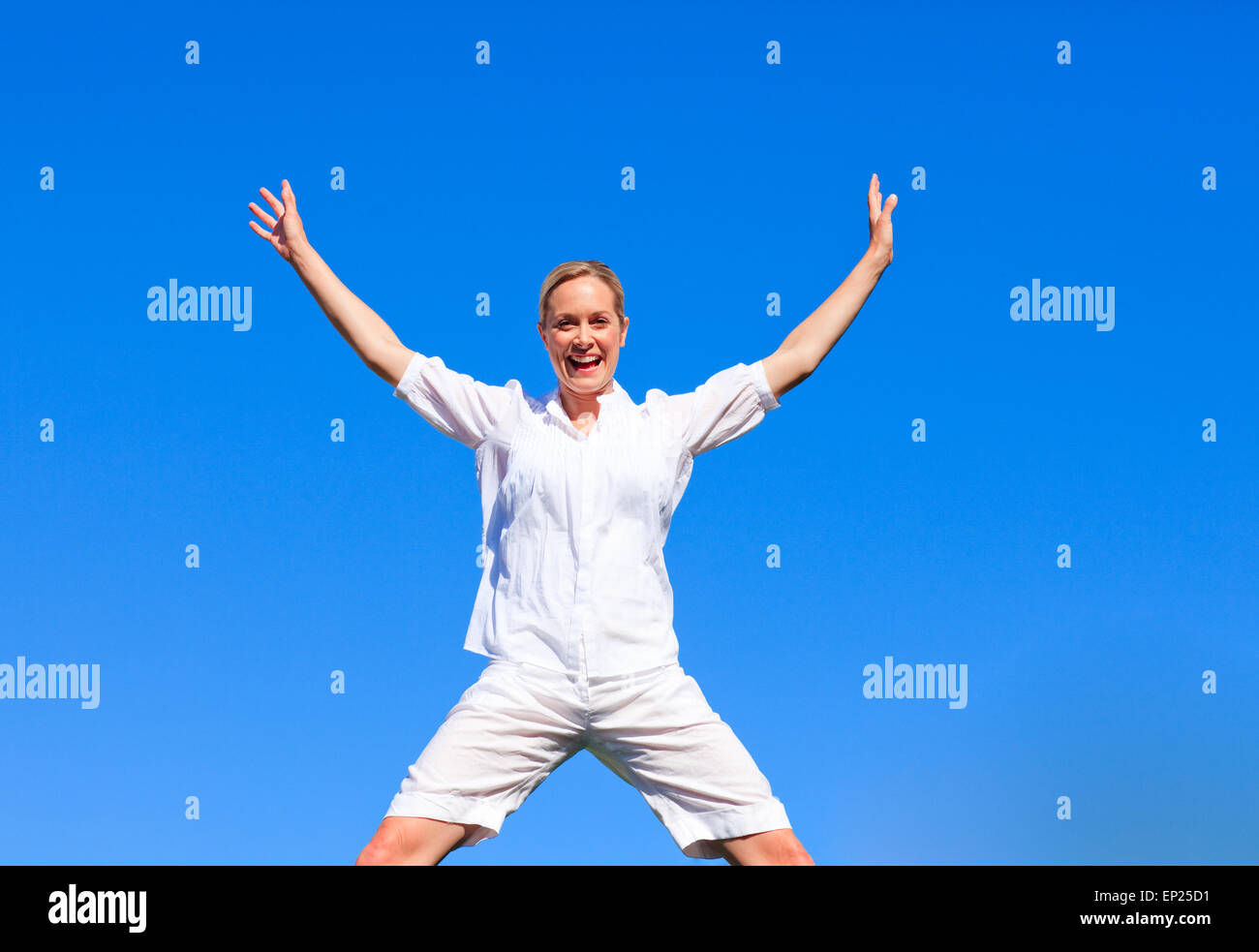 Happy woman jumping against blue sky Stock Photo - Alamy