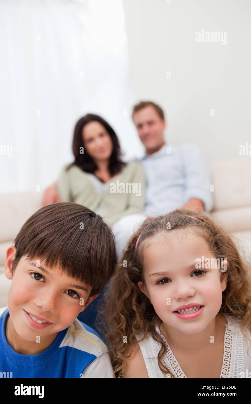 Children sitting in the living room with parents behind them Stock Photo