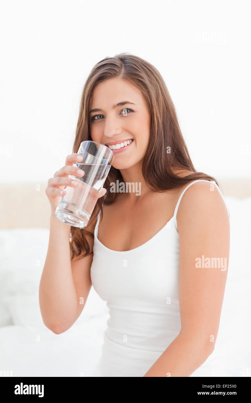 Woman smiles with a glass of water in hand raised to her mouth Stock ...