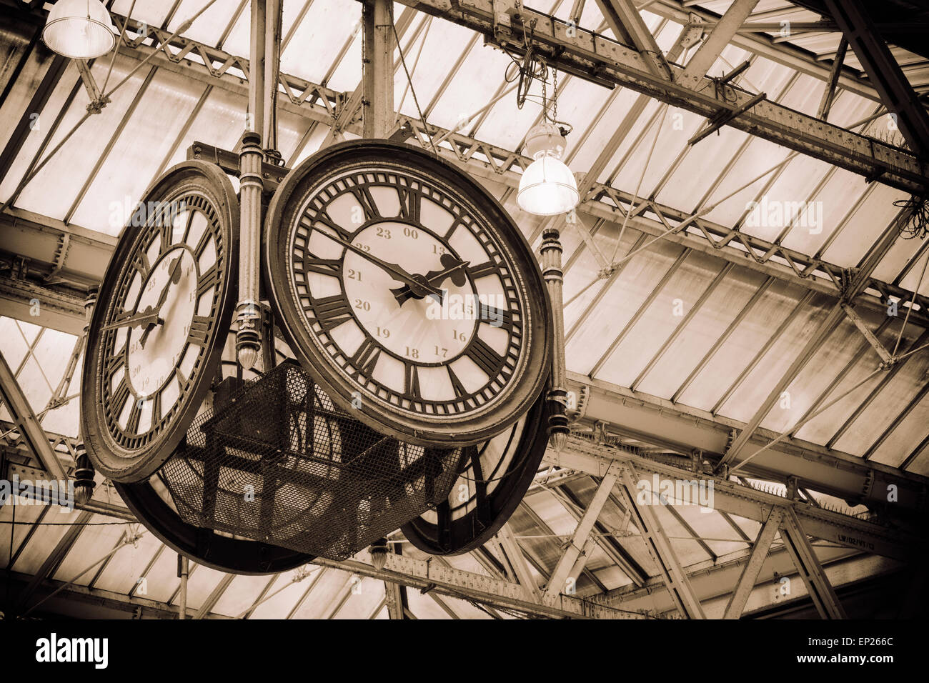 A large four-faced clock hangs in the middle of the main concourse. 'Meeting 'under the clock' is a traditional rendezvous point Stock Photo