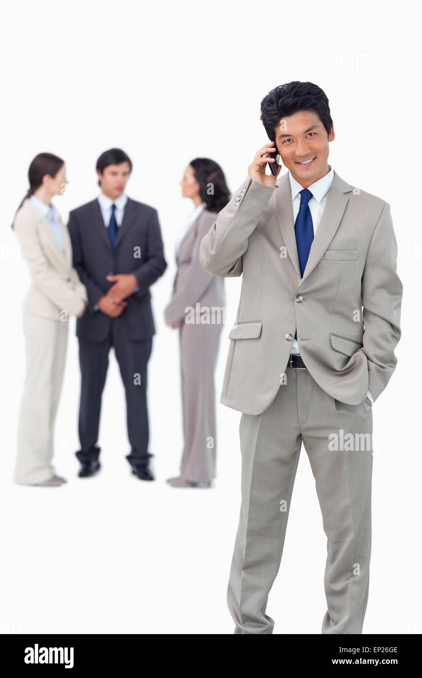 Businessman on cellphone with team behind him Stock Photo - Alamy