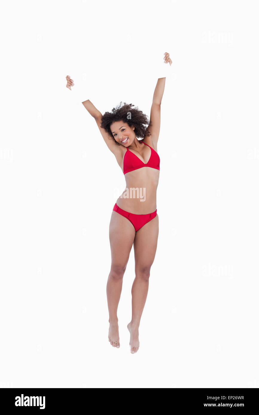 Smiling woman jumping while raising a blank poster above her head Stock Photo