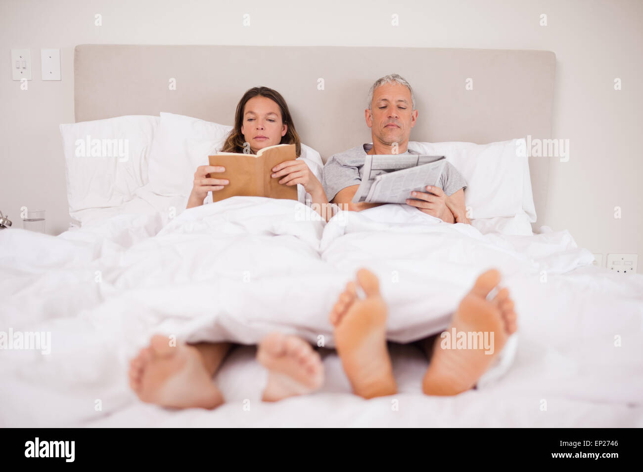 Man reading the news while his wife is reading a book Stock Photo