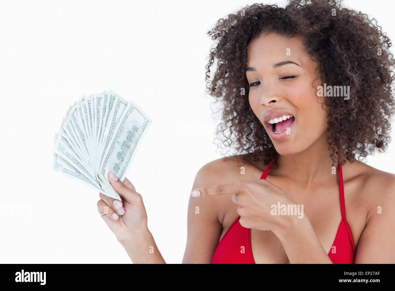 Young woman blinking an eye while holding a fan of notes Stock Photo