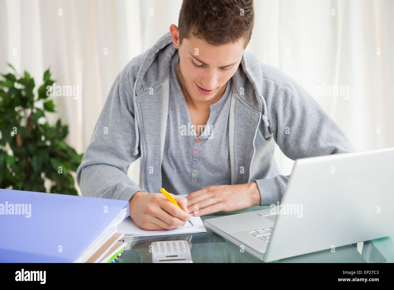 Smiling student doing his homework with a laptop Stock Photo - Alamy