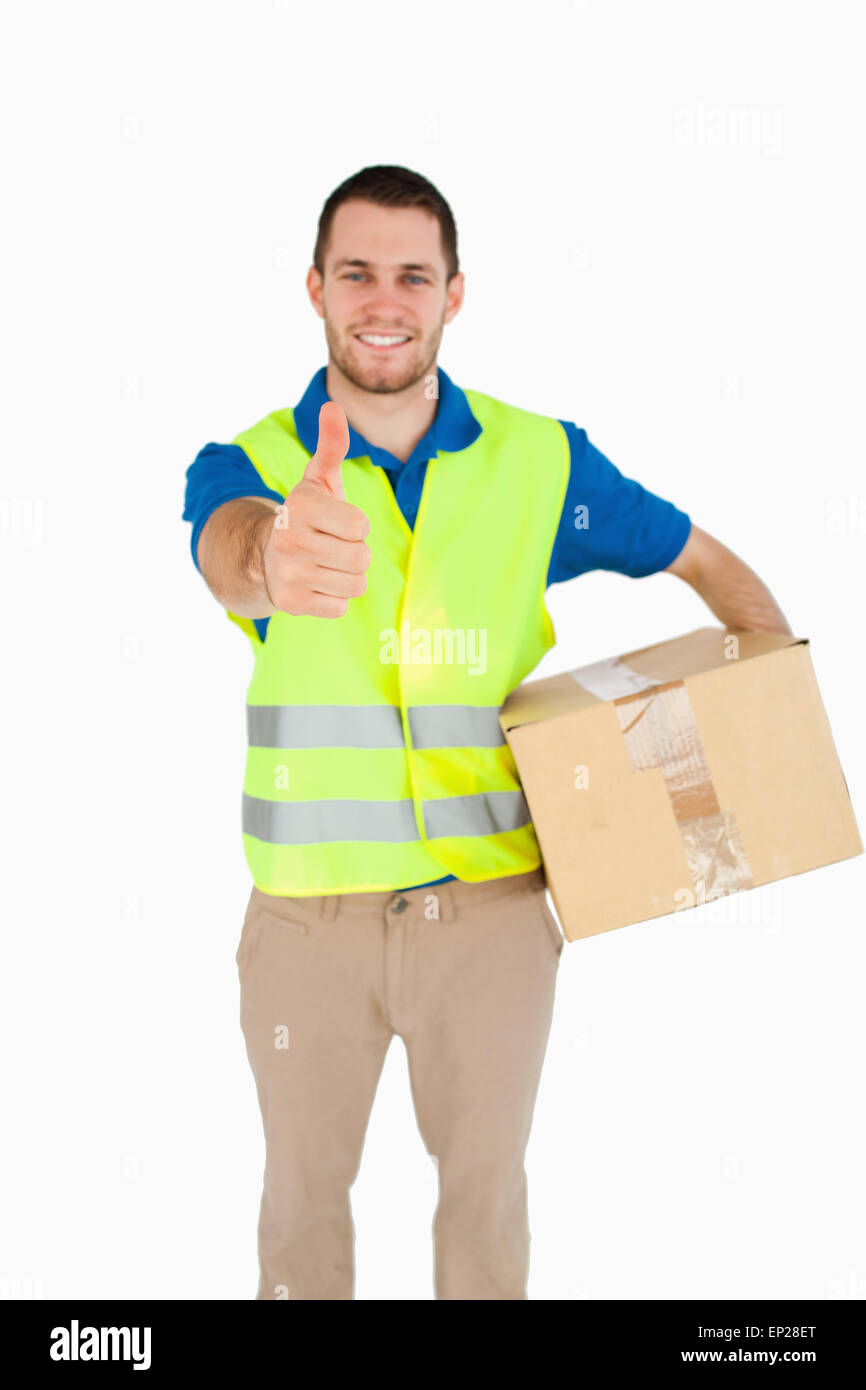 Smiling young delivery man with parcel giving thumb up Stock Photo - Alamy