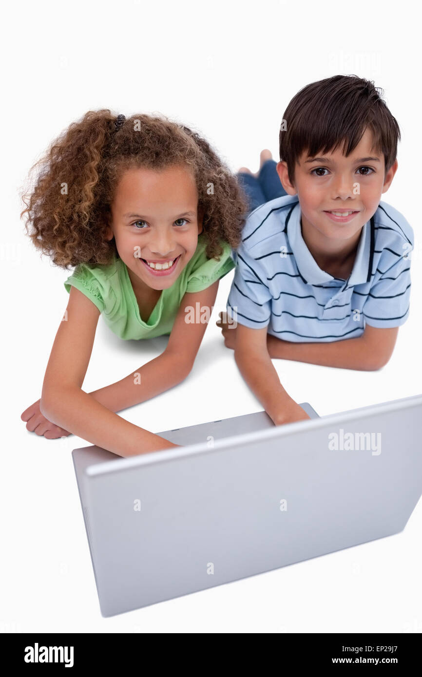 Portrait of children using a notebook while lying on the floor Stock ...