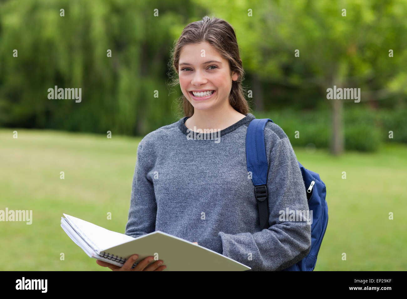 Young happy girl holding her notebook in a park while showing a great ...