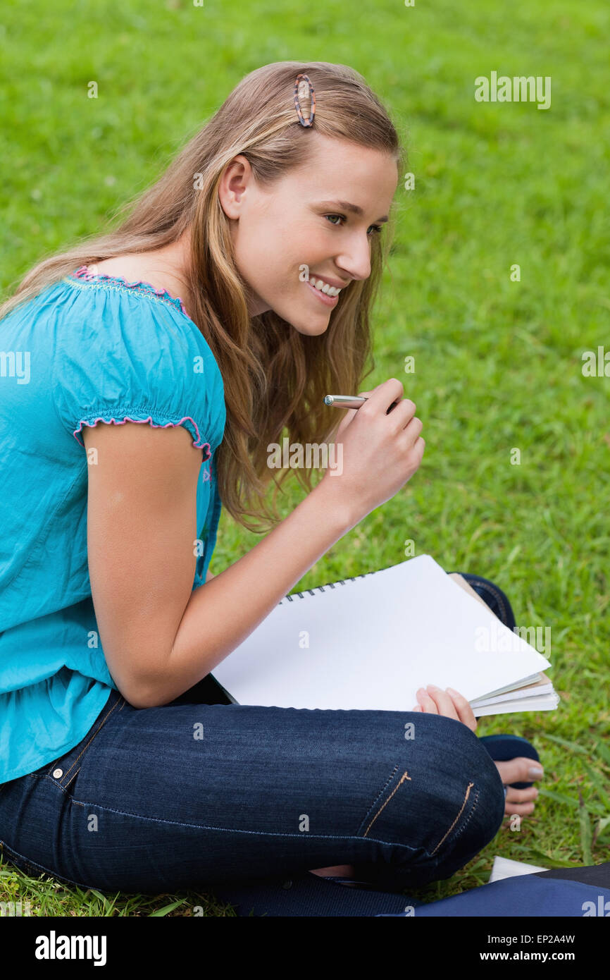 Young smiling girl looking towards the side while writing on her ...
