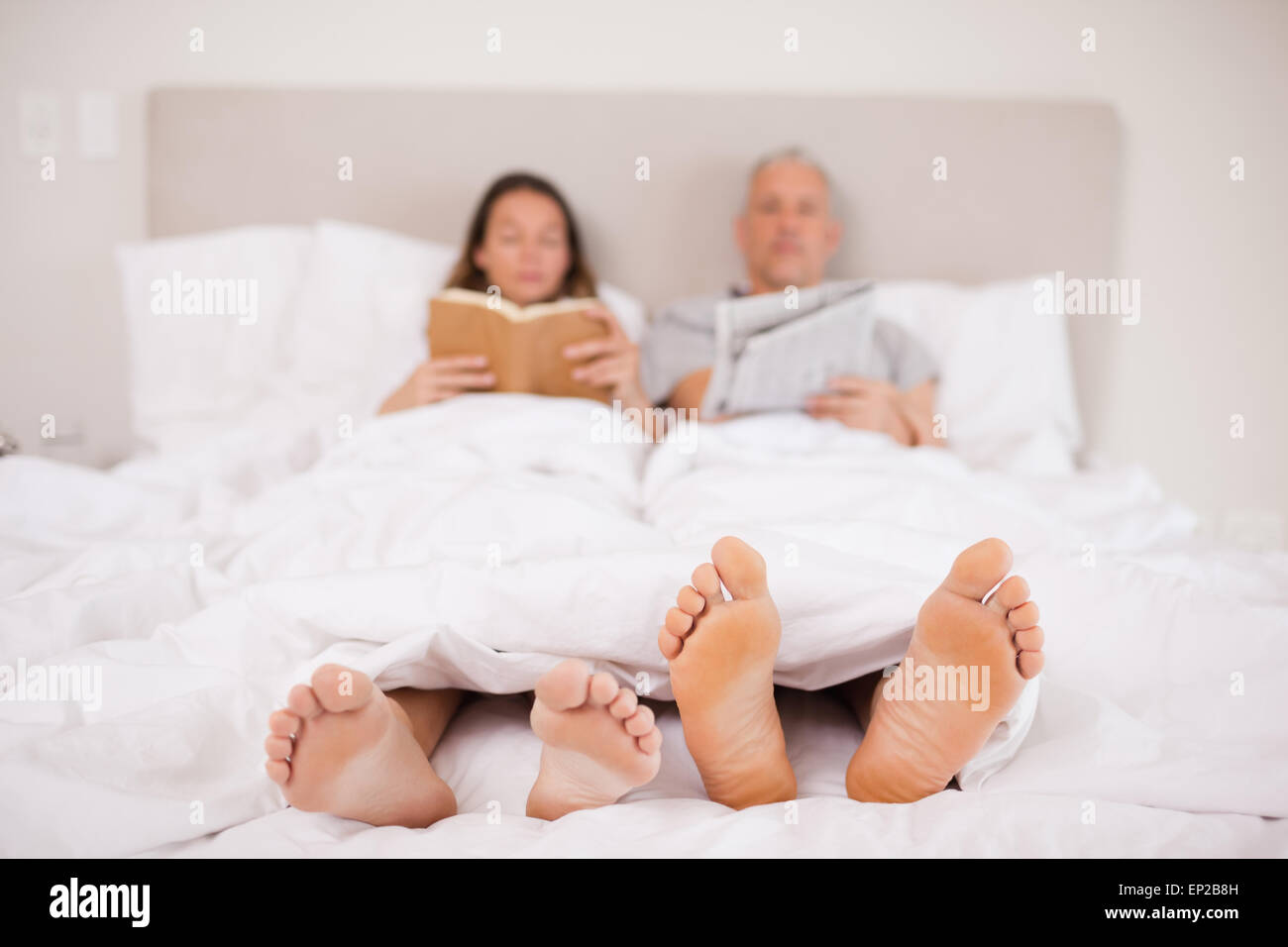 Woman reading a book while her companion is reading the news Stock Photo
