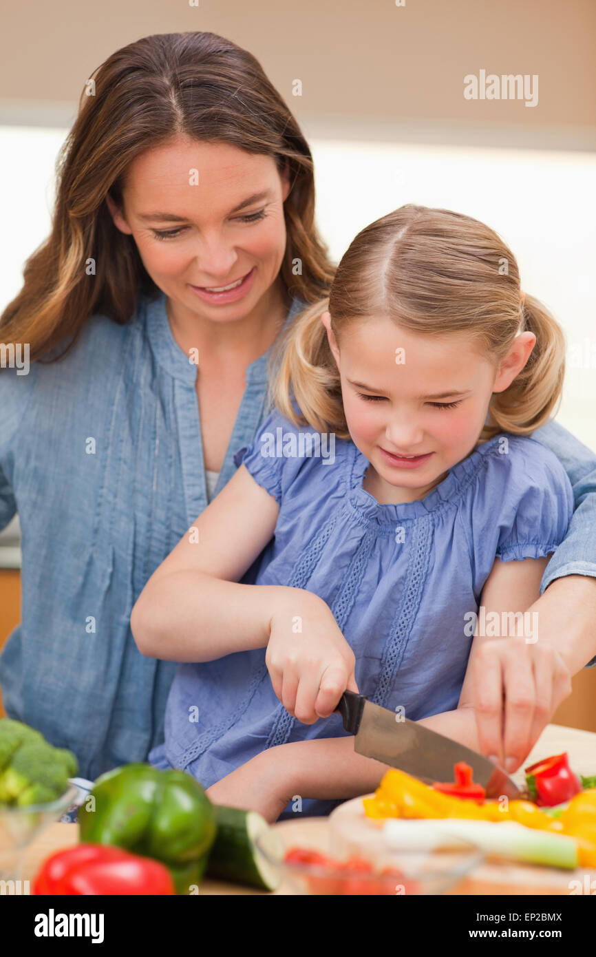 Portrait of a mother slicing bell pepper with her daughter Stock Photo
