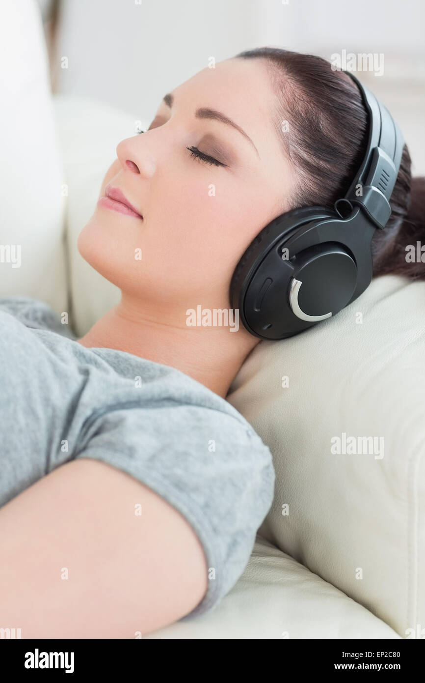 Young woman lying on the couch and listening to music Stock Photo - Alamy