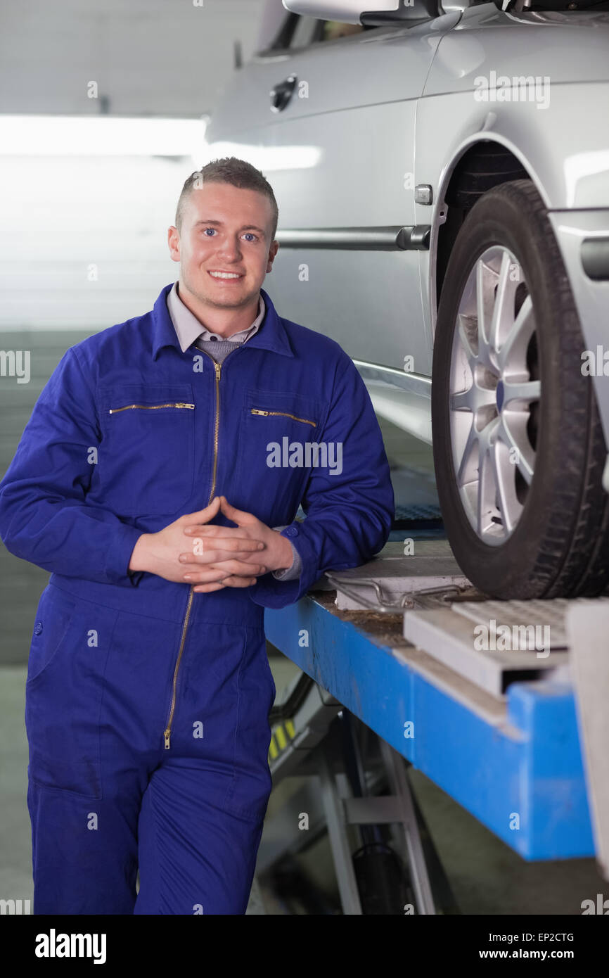 Front view of a smiling mechanic next to a car Stock Photo - Alamy