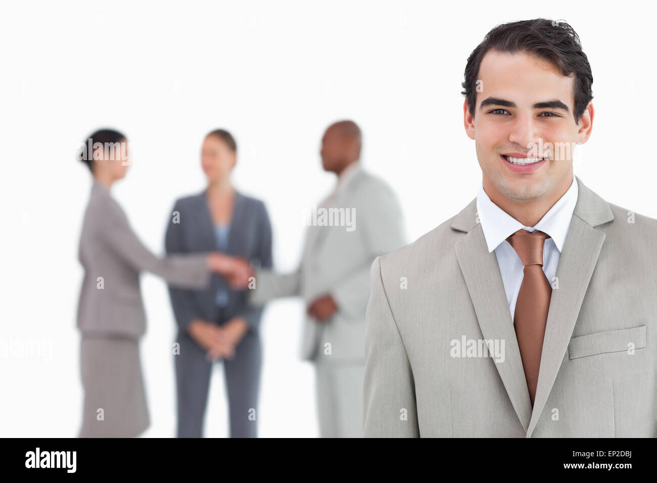 Smiling salesman with businesspeople behind him Stock Photo - Alamy