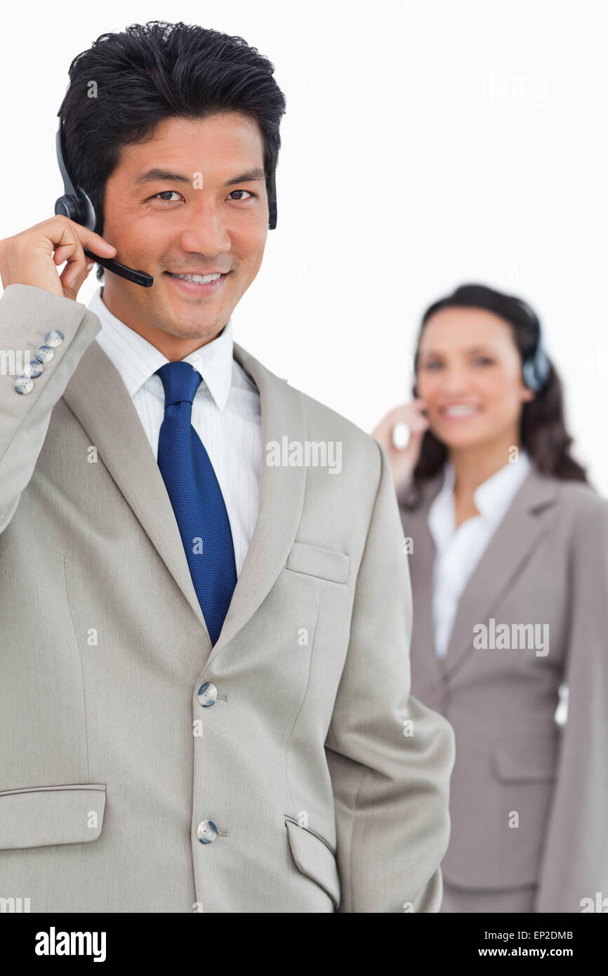 Smiling customer support employee with colleague behind him Stock Photo ...