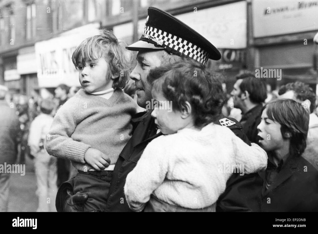 Fire at Maryhill Road Glasgow. Fire breaks out in an unoccupied furniture shop spreading along the row of shops and trapping some families in their homes above. Fifty families were made homeless and one woman and one Fire Officer lost their lives. Saturday, 18th November 1972. Pictured Robert and Isobel McPhee aged three and four, held in safety by a police officer after their rescue from the fire. Stock Photo