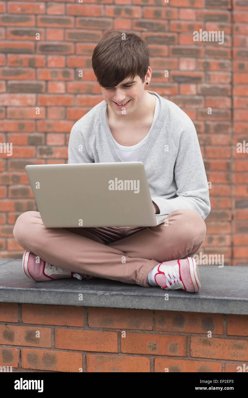 Man sitting cross legged and using laptop outside Stock Photo - Alamy