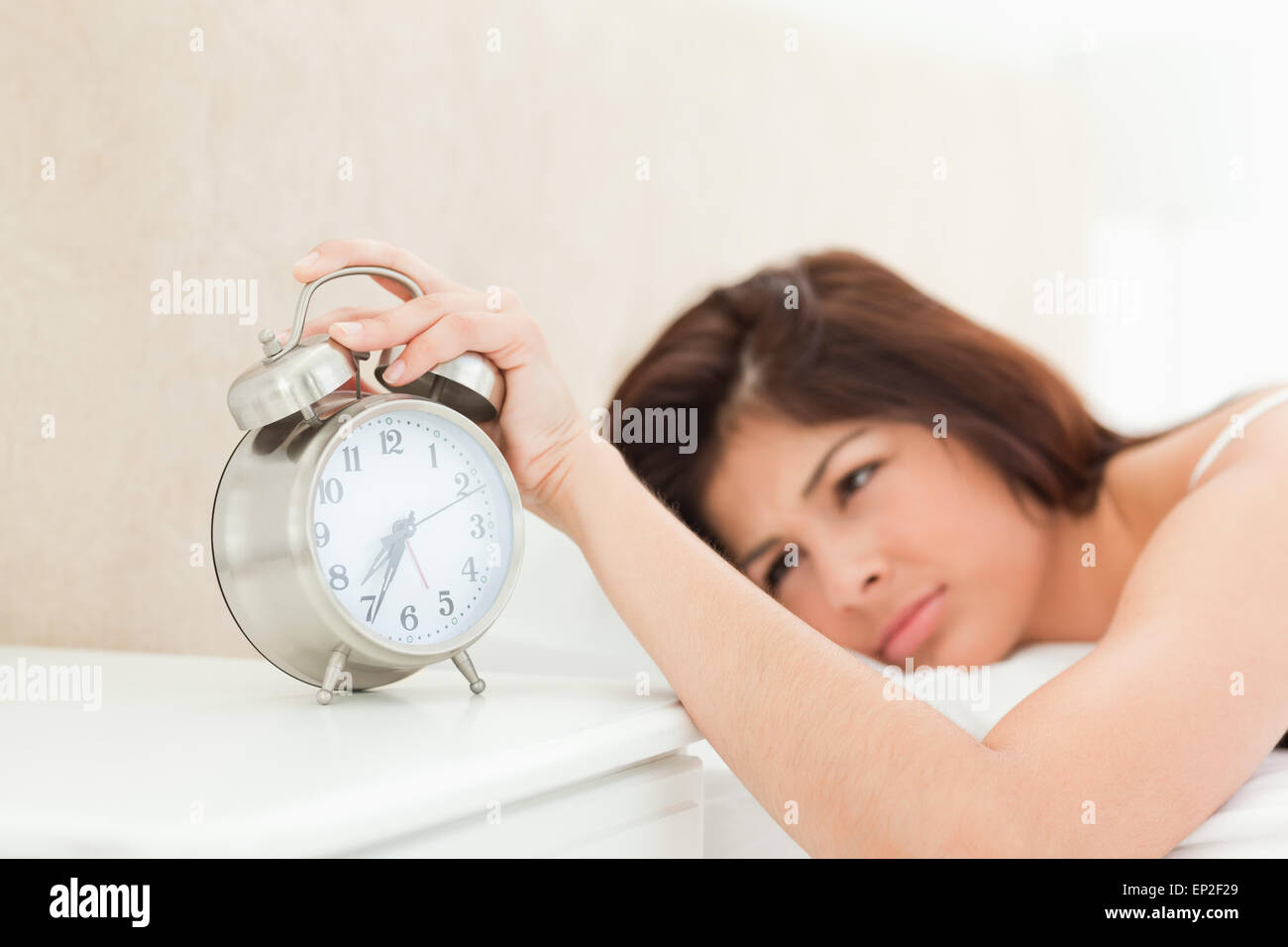 An alarm clock showing the time, being silenced by a woman lying on her bed Stock Photo Alamy