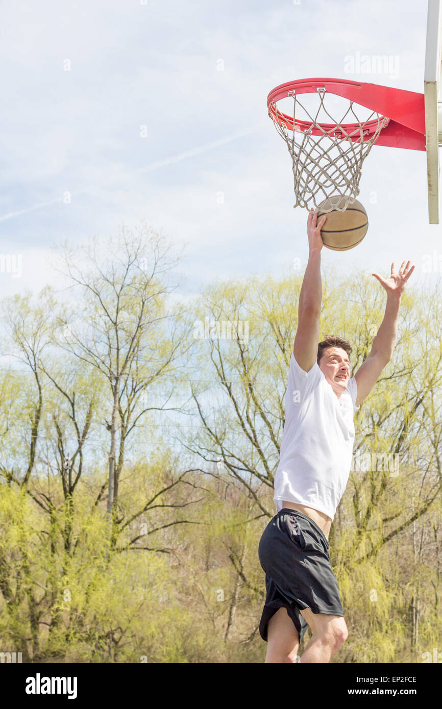 Young man doing basketball trick shots as he leaps through the air