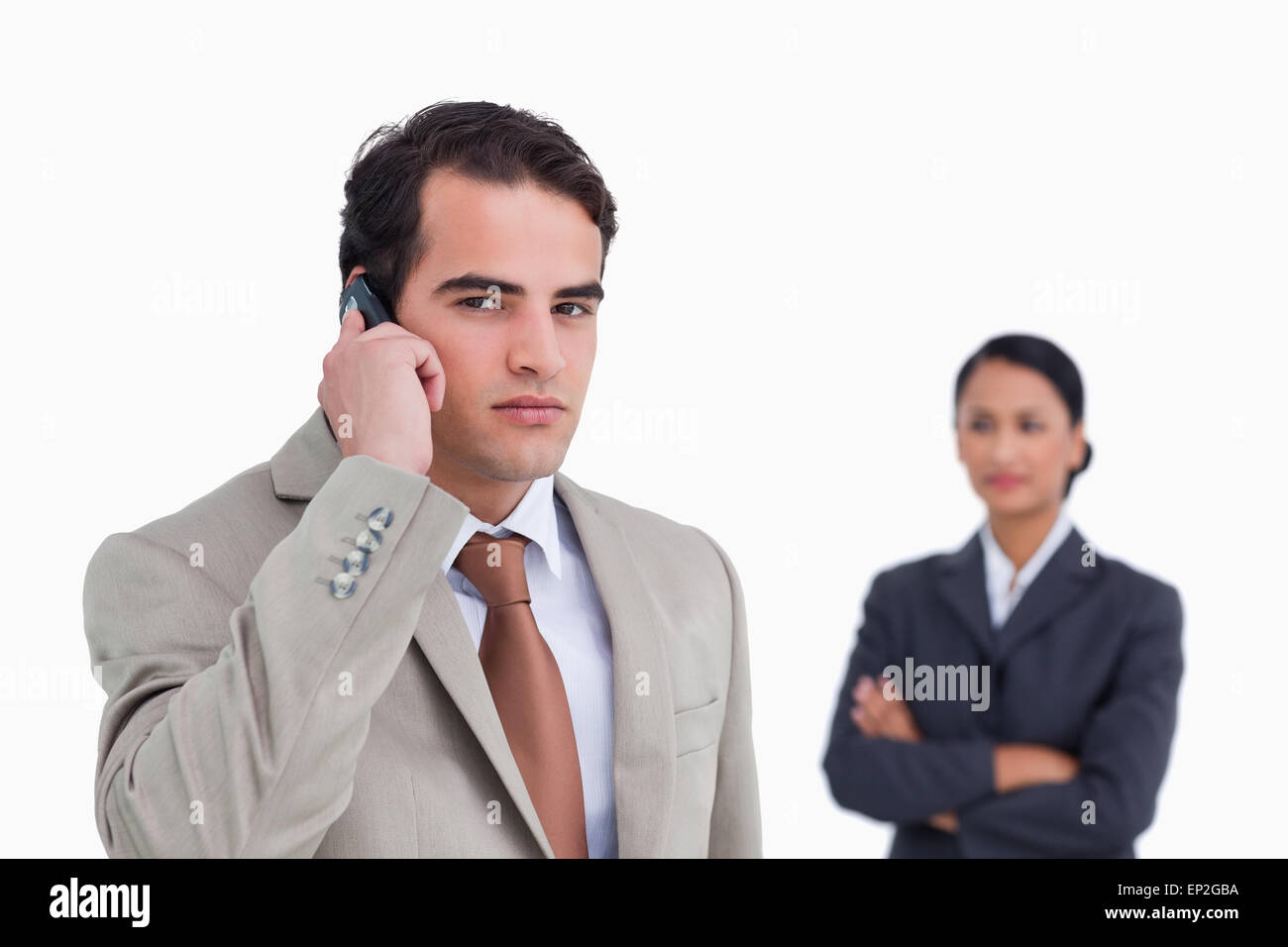 Serious salesman on his cellphone with colleague behind him Stock Photo ...