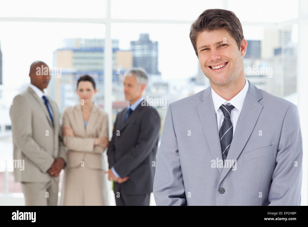 Young smiling manager standing upright with his team behind him Stock ...
