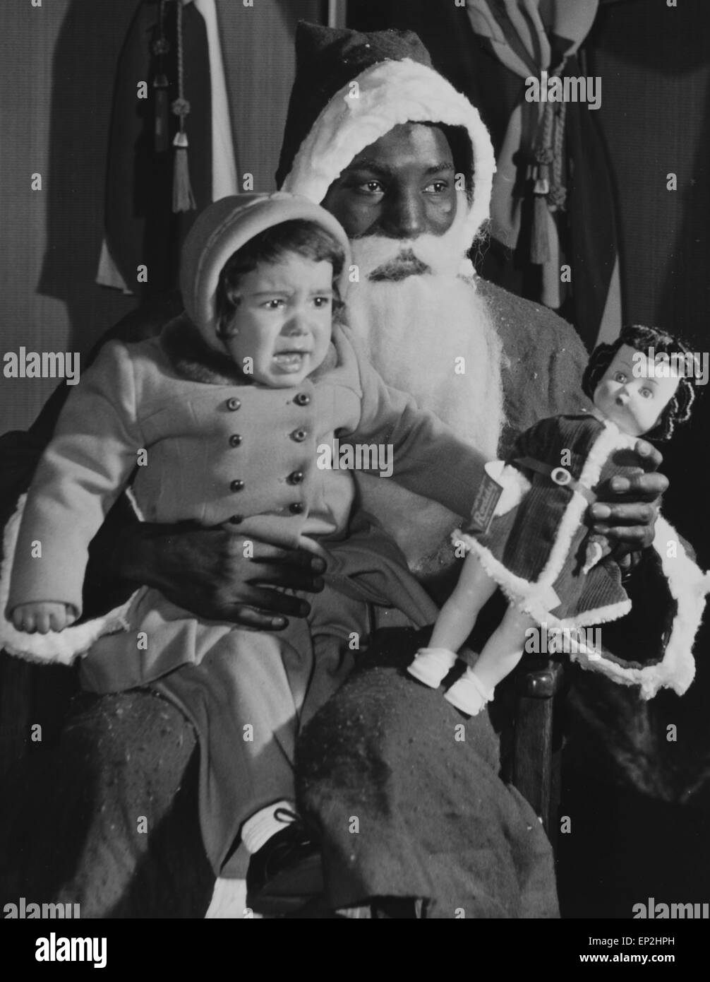 Sandy Manuel, the Nigerian Boxer acting as Santa Claus at the Commonwealth Exhibition presenting a doll to the 75,000th visitor Deobrah Connor, or George Street, Liverpool who also celebrated her 2nd birthday. 4th December 1958 Stock Photo