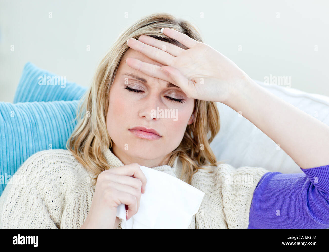 Sick woman with headache lying on the sofa in the livingroom Stock