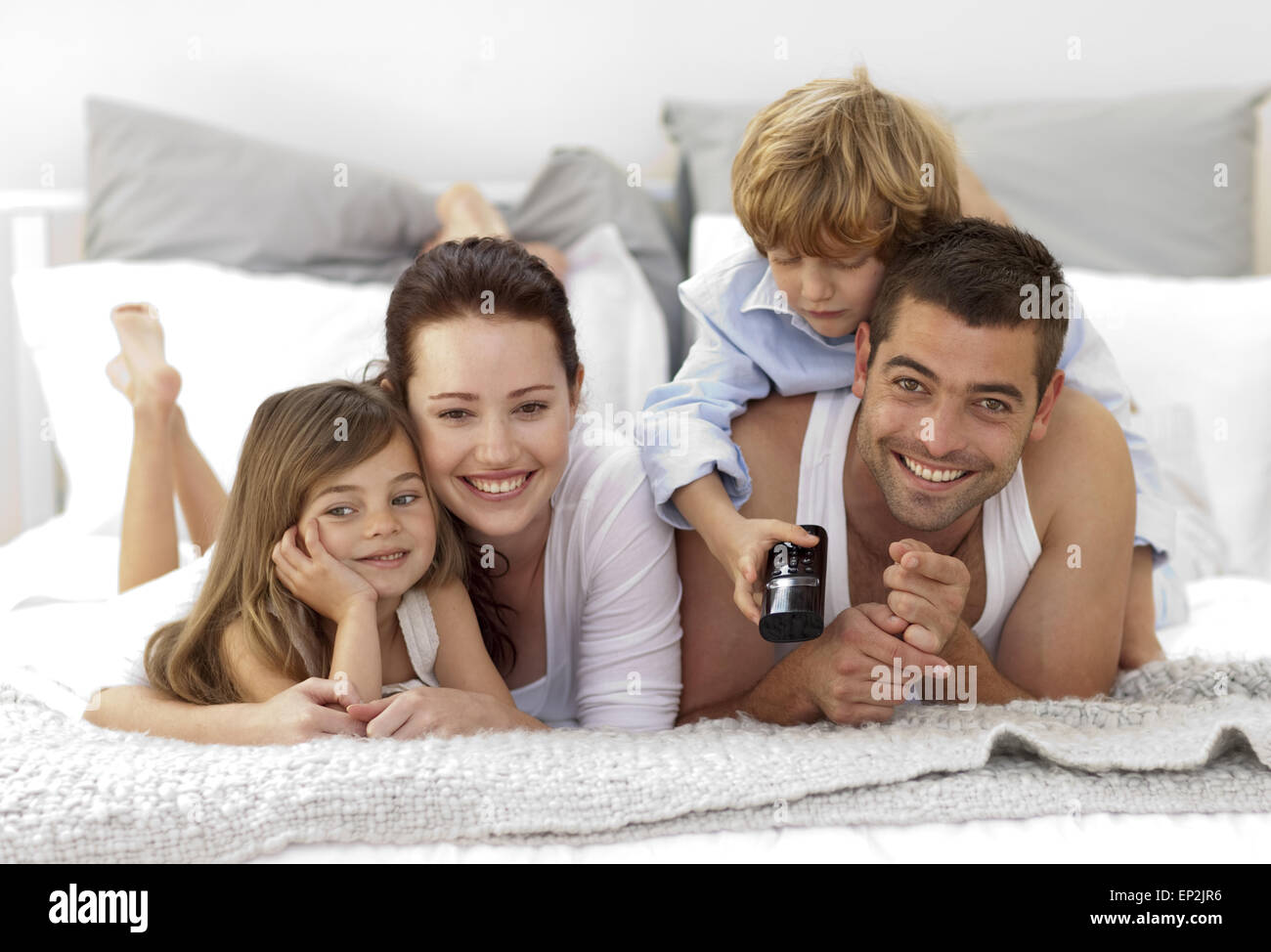 Family lying in bed watching television Stock Photo