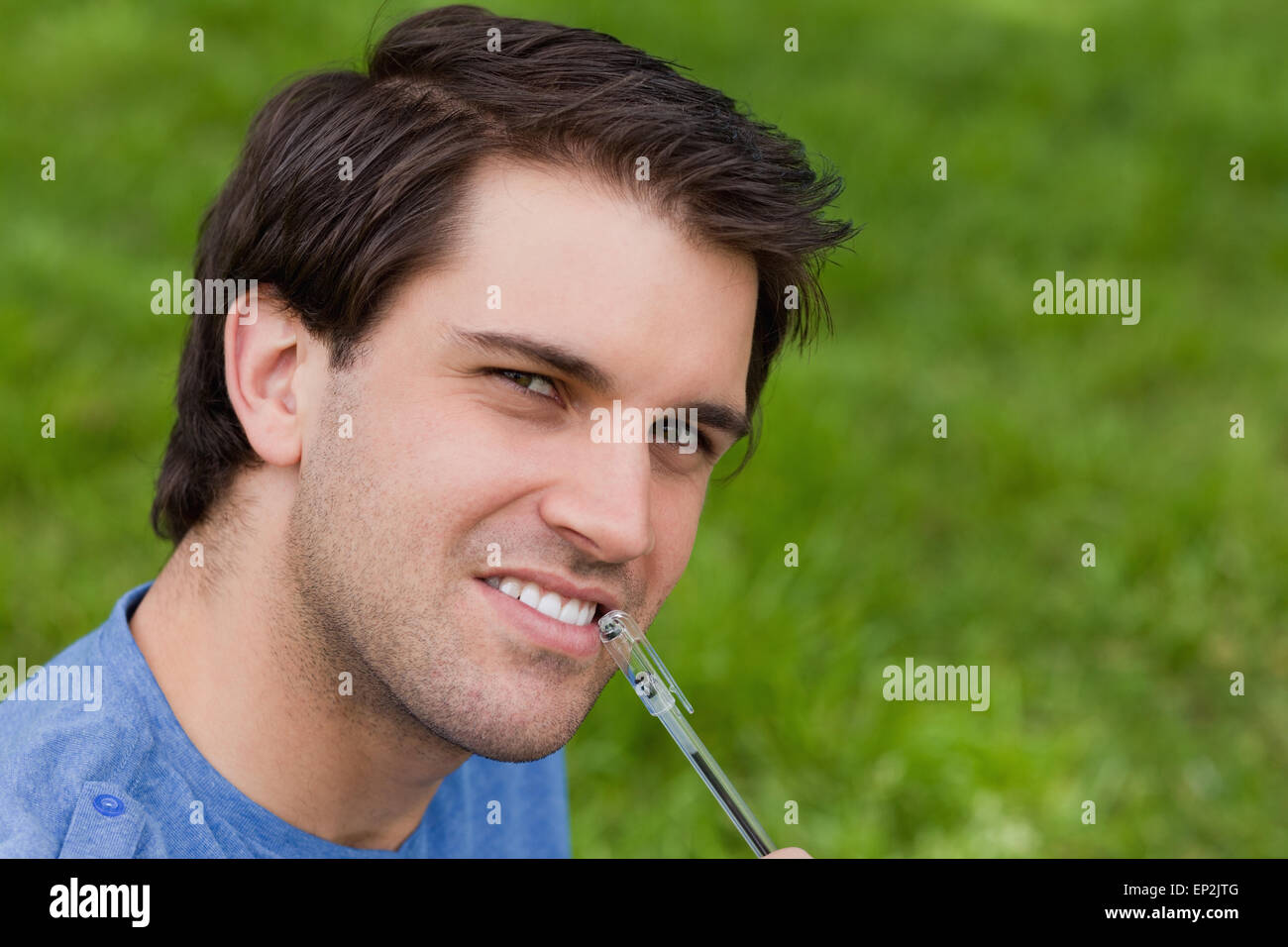 Young thoughtful man looking at the camera while holding his pen Stock Photo