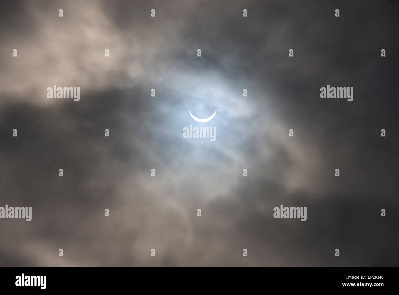Solar eclipse glimpsed through a gap in dark rain clouds on 30 March 2015, Sheffield UK Stock Photo