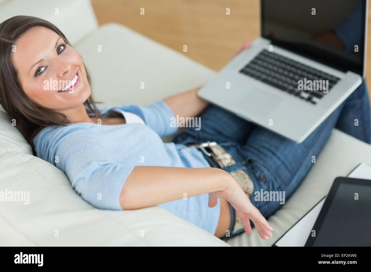 Happy woman using her laptop and sitting back on couch Stock Photo - Alamy