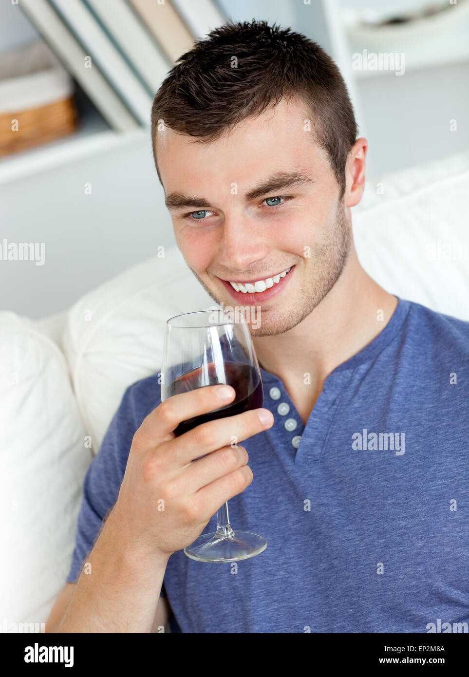 Animated young man drinking wine sitting on the sofa Stock Photo - Alamy