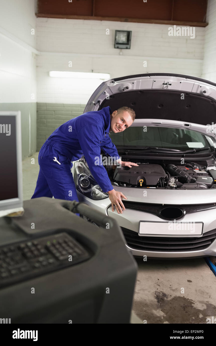 Smiling mechanic leaning on a car next to a computer Stock Photo - Alamy