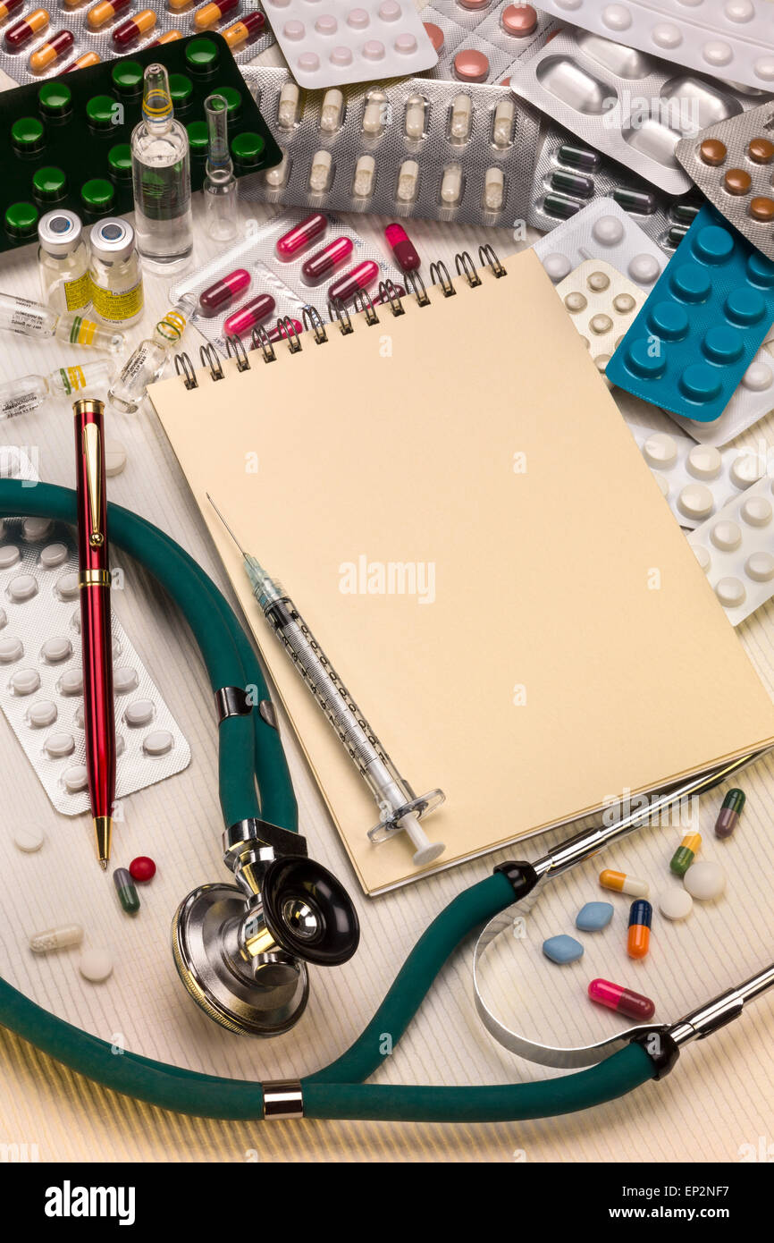 A doctors stethoscope and drugs with syringes and a notepad and pen - with space for text. Stock Photo