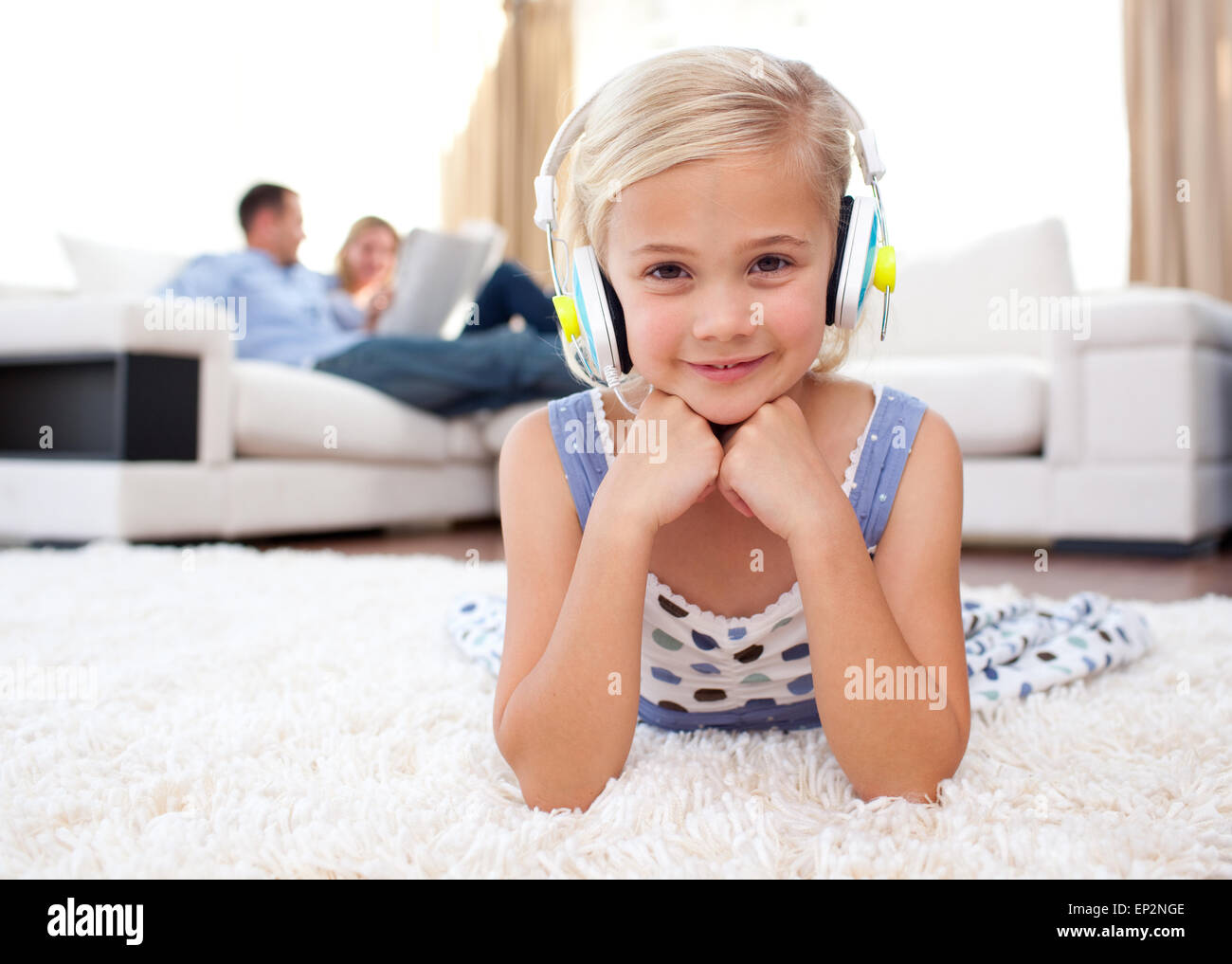 Smiling little girl listening music lying on the floor Stock Photo - Alamy