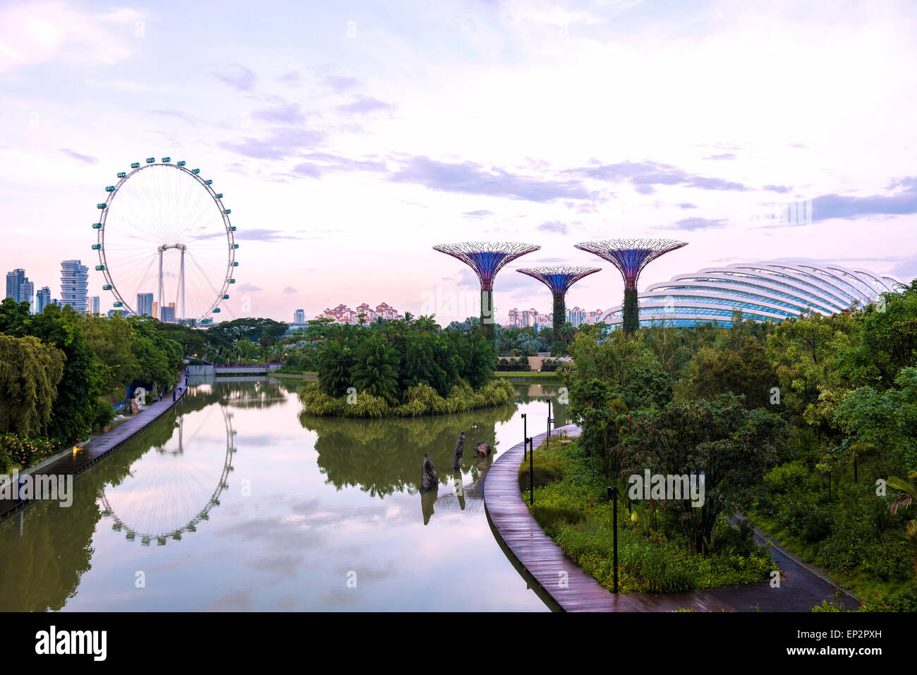 Singapore, Gardens by the Bay with Supertrees, Flower Dome and Singapore Flyer reflected in Dragonfly lake at sunset Stock Photo