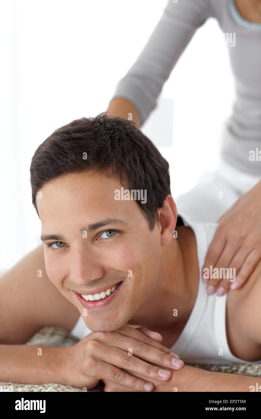 Cheerful man enjoying a back massage from his girlfriend on their bed