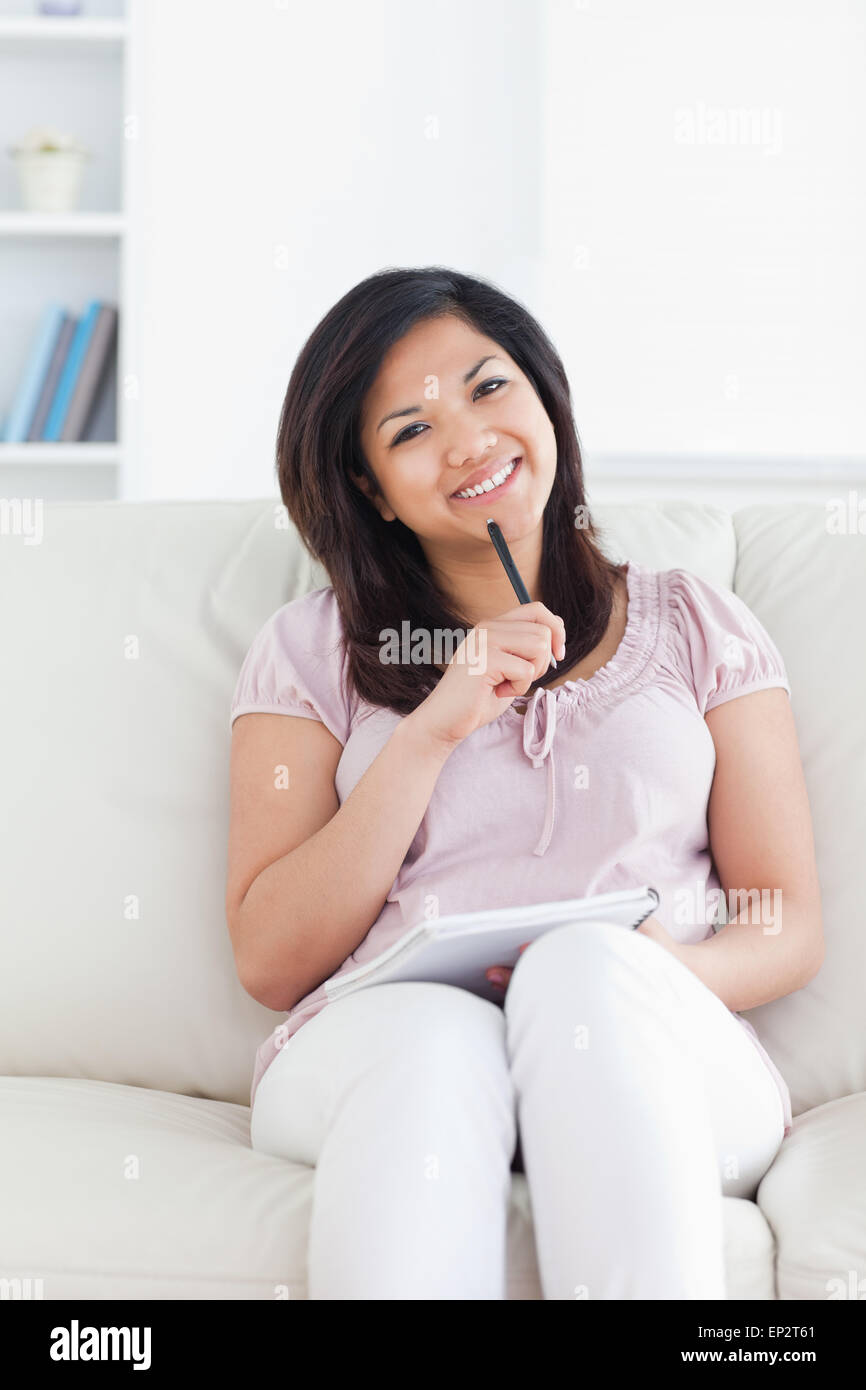 Woman smiling and holding a pen and a notebook Stock Photo - Alamy